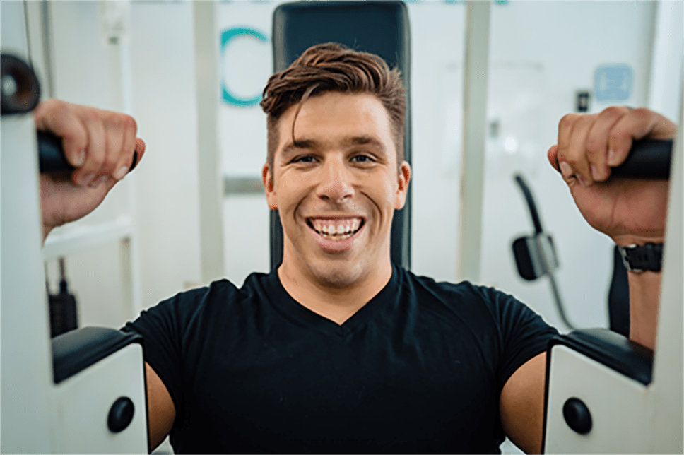 Brandon sonriendo y disfrutando de su sesión de entrenamiento en el gimnasio