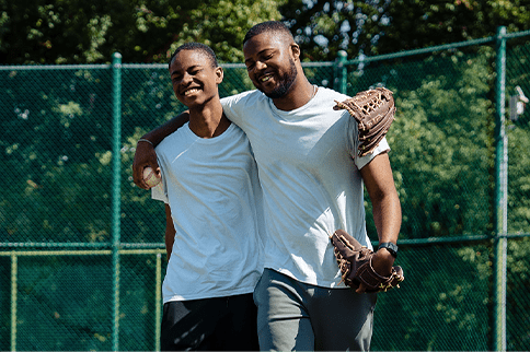 Austin sonriendo con guantes de béisbol y abrazando a su hermano